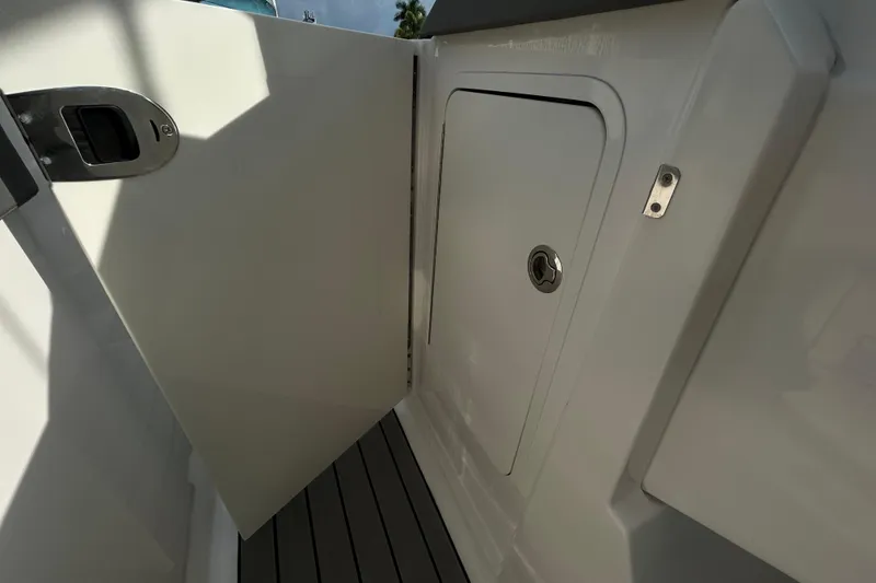 Slide: The Image of 2024 Sea Ray SLX 310 Outboard storage compartment with open door, showcasing sleek design. - 84