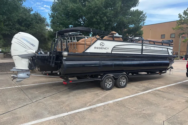 The Image of 2018 Regency 254 LE3 Sport pontoon boat on trailer, parked outdoors. - 0
