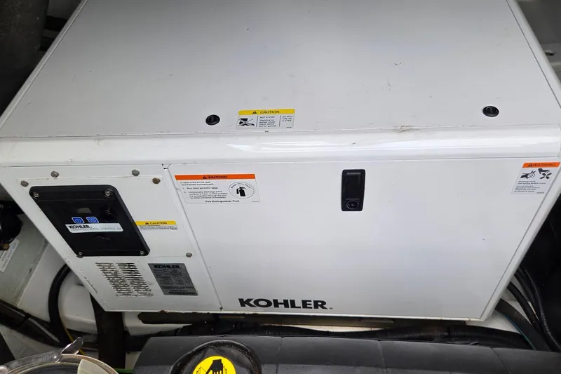 Slide: The Image of Kohler generator in 2020 Aquila 44 Yacht engine room, featuring control panel and safety warnings. - 47