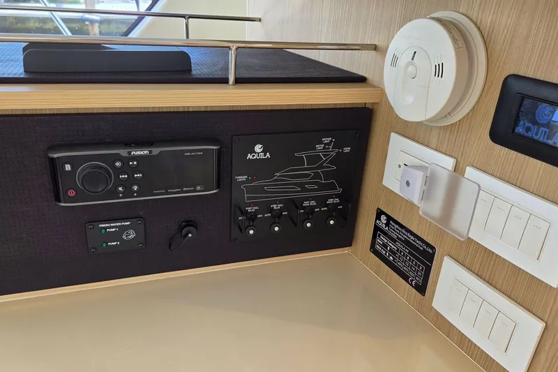 Slide: The Image of Control panel of a 2020 Aquila 44 Yacht with various switches and a smoke detector. - 49