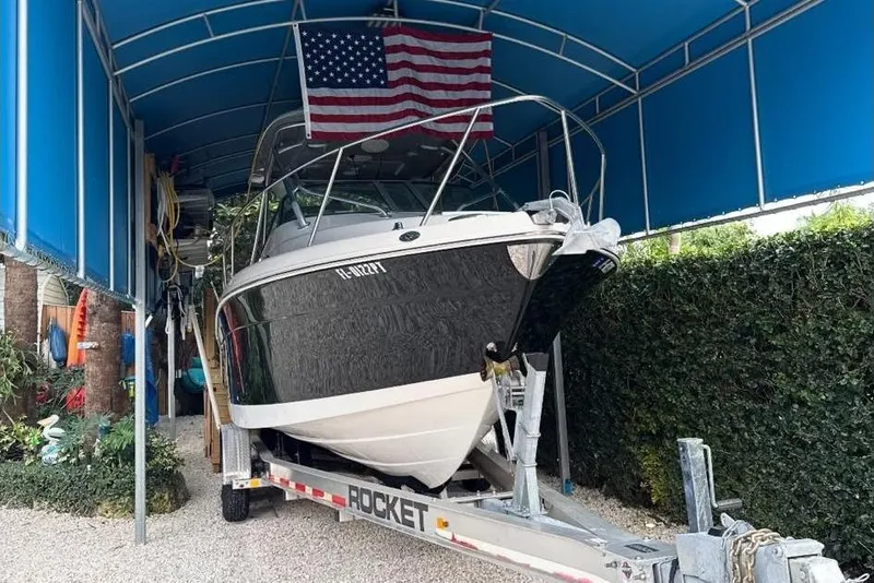 The Image of 2014 Robalo R265 Walkaround boat on trailer under blue canopy. - 0
