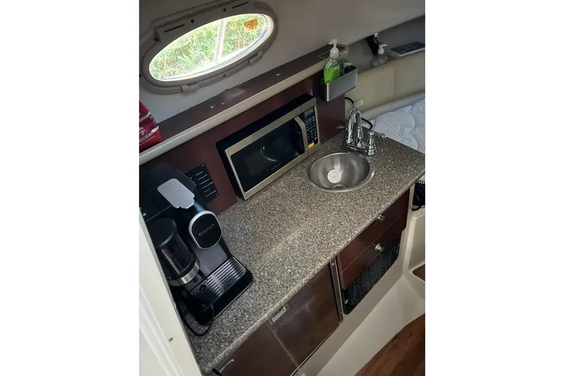 Slide: The Image of 2014 Robalo R265 Walkaround cabin with kitchenette, featuring sink, microwave, and coffee maker. - 10