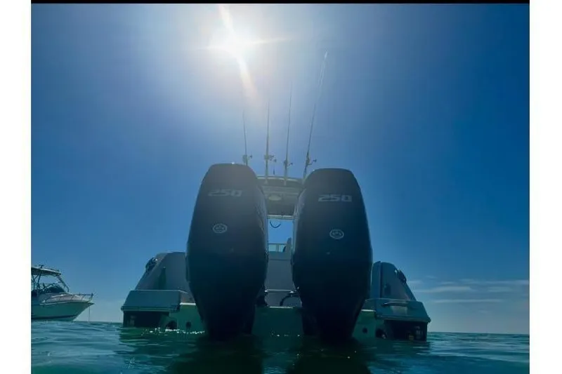 Slide: The Image of 2014 Robalo R265 Walkaround boat with dual engines on calm water under bright sun. - 3