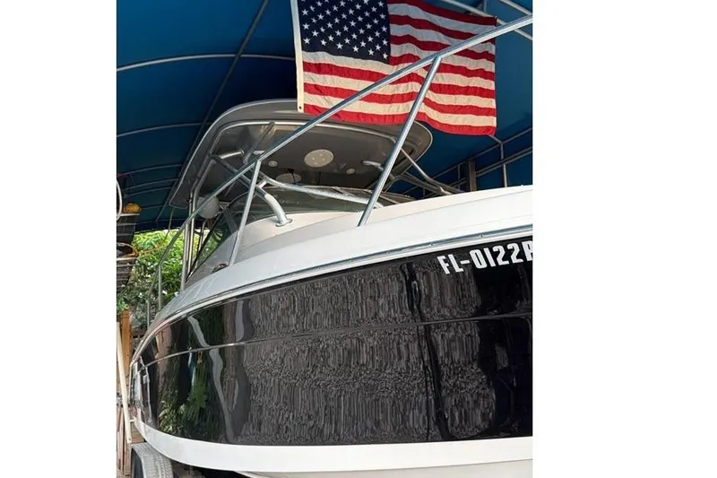 Slide: The Image of 2014 Robalo R265 Walkaround boat under blue canopy with American flag. - 4