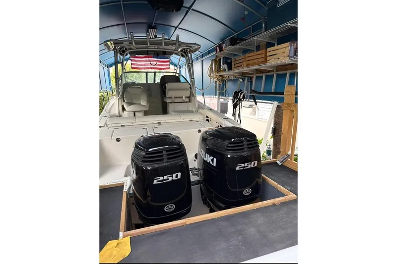 Slide: The Image of 2014 Robalo R265 Walkaround boat with dual Suzuki 250 engines in a covered storage area. - 6