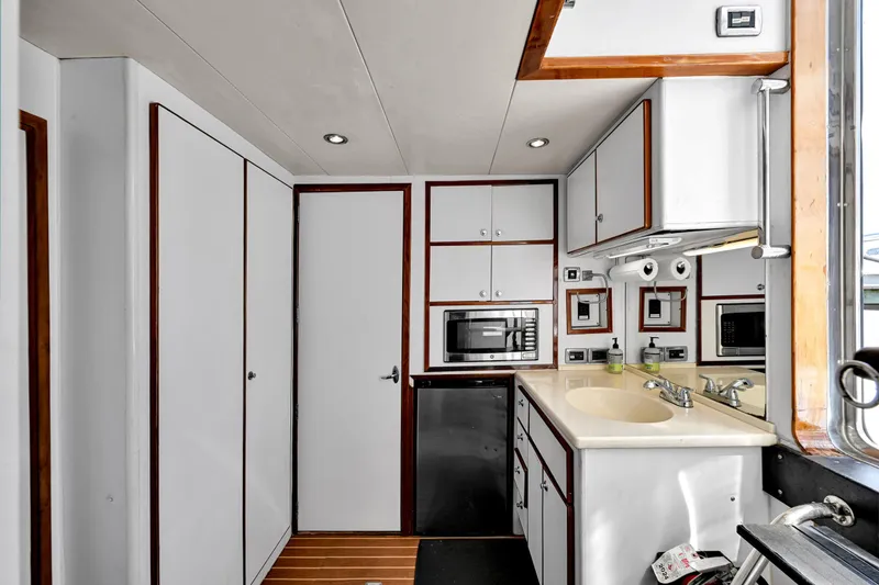 Slide: The Image of Compact kitchen in a 2001 Hargrave 94 yacht, featuring modern appliances and sleek cabinetry. - 52