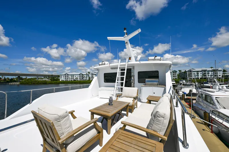 Slide: The Image of Luxurious 2001 Hargrave 94 yacht deck with seating, docked under a clear blue sky. - 75