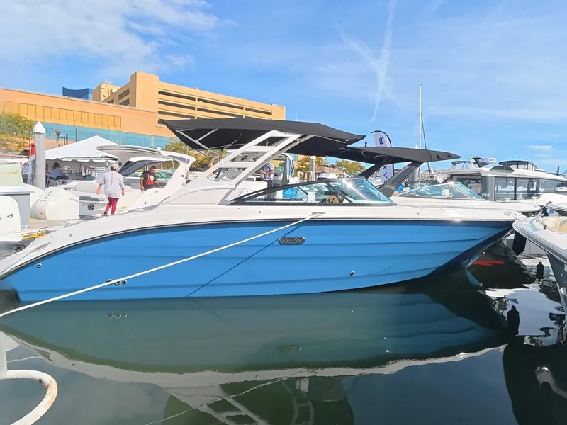 Slide: The Image of A blue Sea Ray SDX 270 Outboard boat is docked in the water, surrounded by other boats. - 0