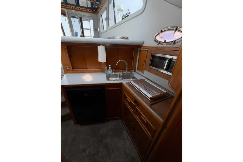 Slide: The Image of 1990 Mediterranean Sport Fish boat kitchen with wooden cabinets, sink, and microwave. - 15