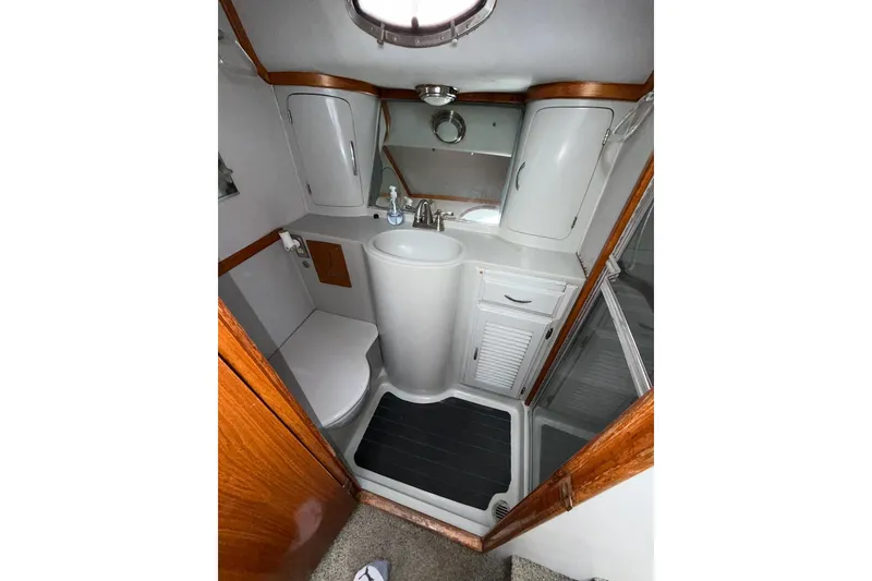 Slide: The Image of Compact bathroom in a 1990 Mediterranean Sport Fish boat, featuring a sink, toilet, and storage cabinets. - 16