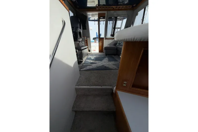 Slide: The Image of Interior view of a 1990 Mediterranean Sport Fish boat, featuring carpeted steps and seating area. - 18