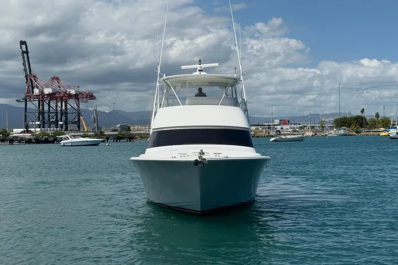 Slide: The Image of 2012 Viking 50 Convertible yacht in harbor, with industrial cranes and cloudy sky backdrop. - 4