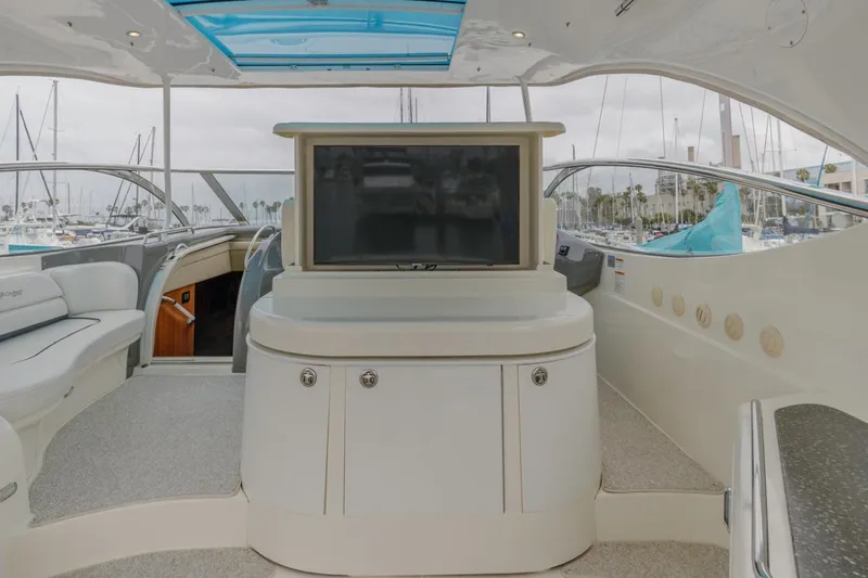 Slide: The Image of 2007 Cruisers Yachts 560 Express interior with TV, seating, and marina view. - 12