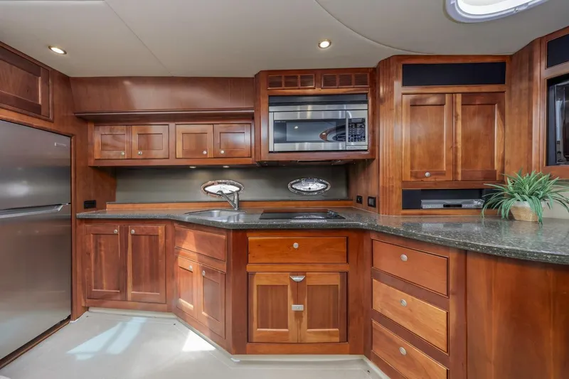 Slide: The Image of Luxurious 2007 Cruisers Yachts 560 Express kitchen with wood cabinetry and modern appliances. - 17