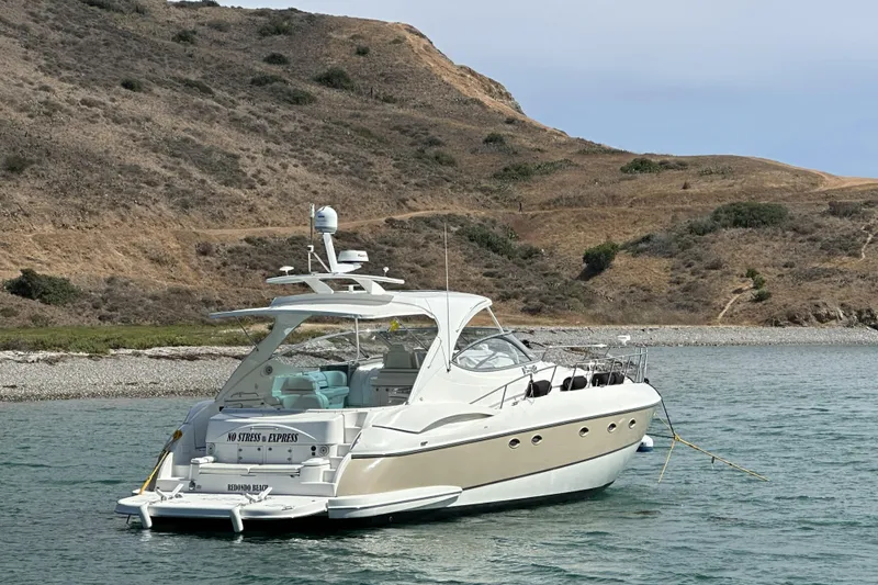 Slide: The Image of 2007 Cruisers Yachts 560 Express anchored near rocky shoreline. - 2