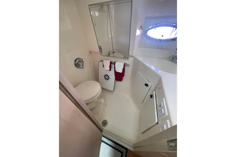 Slide: The Image of Bathroom interior of 1995 Tiara Yachts 3500 Express, featuring compact design and porthole window. - 11