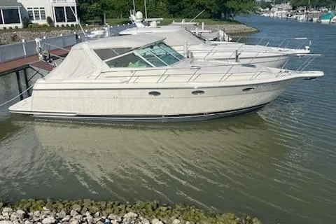 Slide: The Image of 1995 Tiara Express yacht docked on a calm river near a residential area. - 8