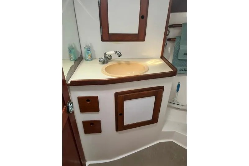 Slide: The Image of 1991 Freedom Yachts 38 bathroom with sink, wooden cabinets, and toiletries. - 26