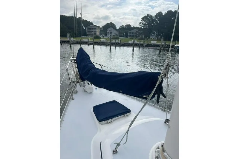 Slide: The Image of 1991 Freedom Yachts 38 sailboat deck with covered sail, docked by waterfront homes. - 3