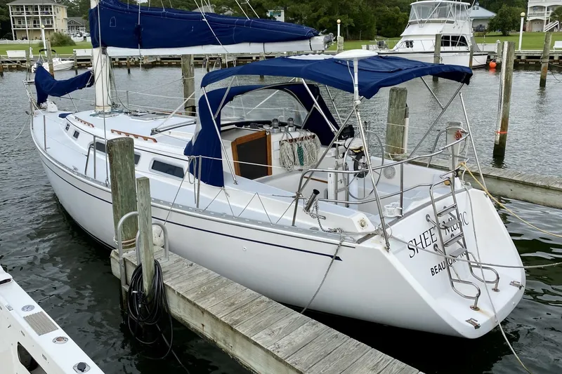 Slide: The Image of Sailboat Freedom 38, 1991 model, docked at marina with blue canopy and white hull. - 2