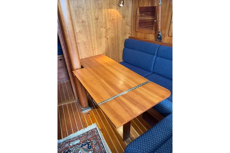 Slide: The Image of 1998 Sabre 362 yacht interior with wooden table and blue cushioned seating. - 21