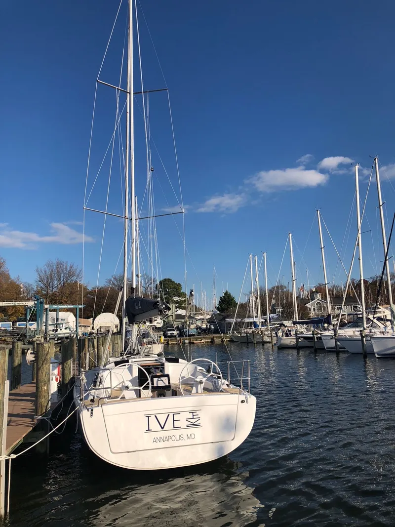 Slide: The Image of A sailboat is docked in a calm harbor, surrounded by other boats and a clear sky. - 2