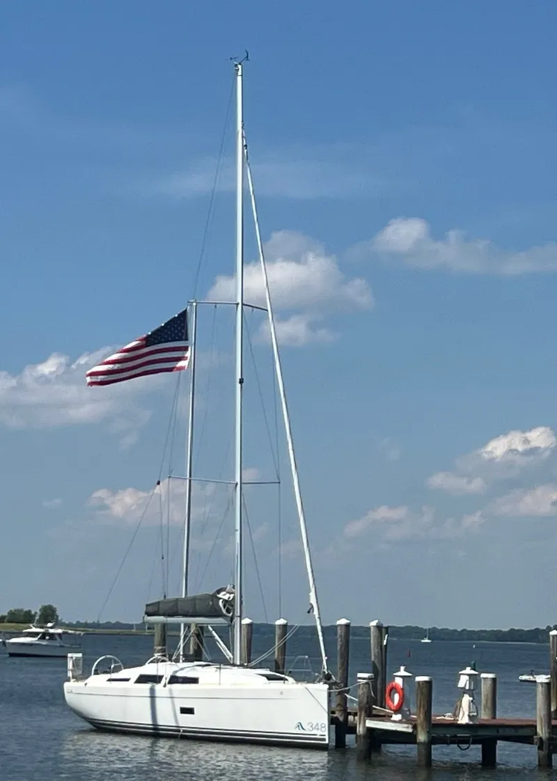 Slide: The Image of A white sailboat docked at a pier, with an American flag waving in the wind. - 3