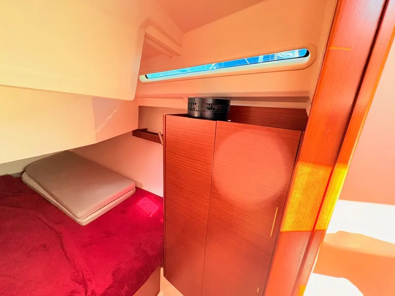 Slide: The Image of Interior of a Hanse 348 yacht with a red bed and wooden cabinet. - 34