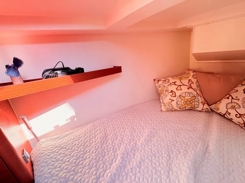 Slide: The Image of A cozy boat bedroom with a bed, decorative pillows, and a shelf with a fan. - 43