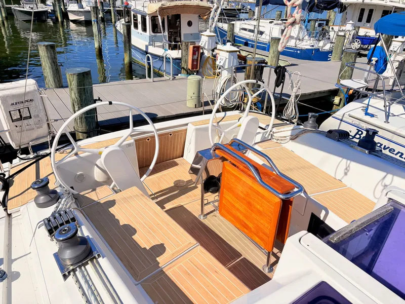 Slide: The Image of The cockpit of a Hanse 348 yacht in a marina, featuring dual steering wheels and wooden flooring. - 6