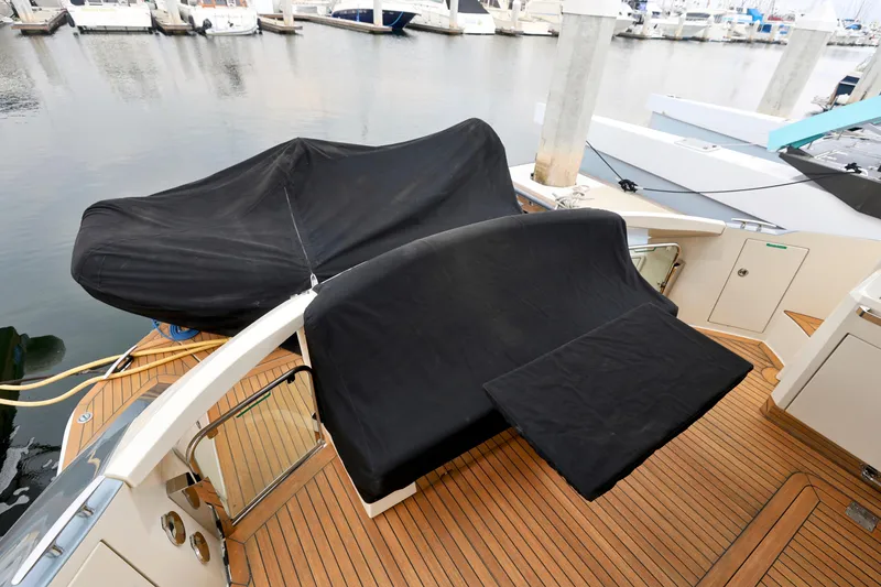 Slide: The Image of 2013 Marquis 500 Sport Bridge yacht with covered seating on teak deck at marina. - 17