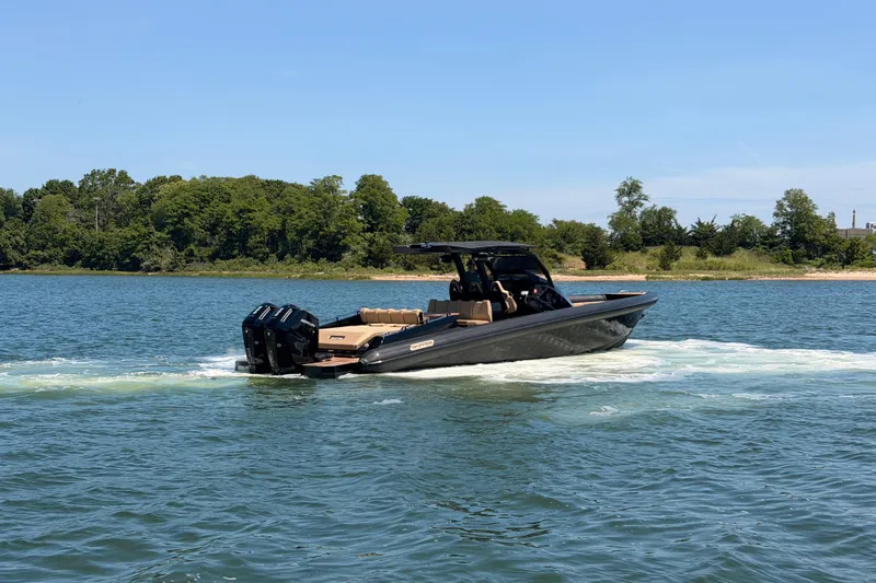 Slide: The Image of 2023 Skipper-BSK 42NC boat cruising on a scenic lake with lush green shoreline. - 10