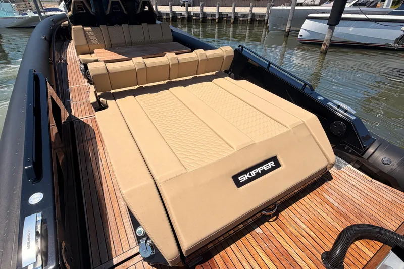Slide: The Image of Luxurious 2023 Skipper-BSK 42NC boat with tan seating and wooden deck, docked at marina. - 13