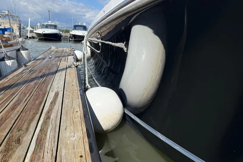 Slide: The Image of 2019 Regulator 34SS boat docked with fenders, wooden pier, and other boats in background. - 3