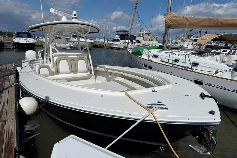Slide: The Image of 2019 Regulator 34SS boat docked at marina, surrounded by other vessels under a partly cloudy sky. - 2