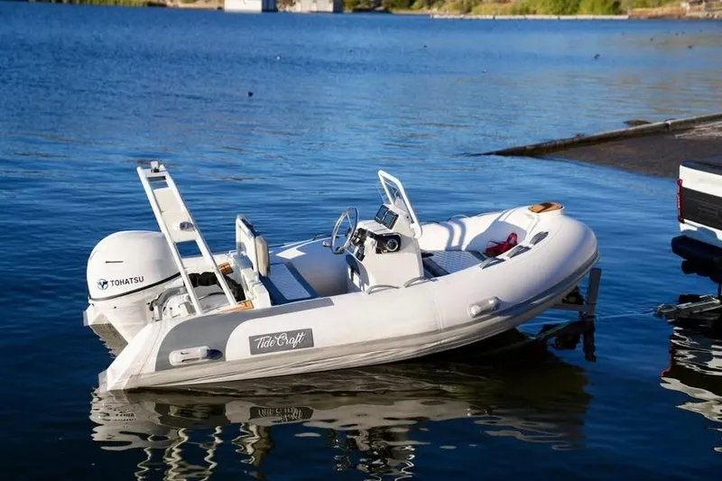 Slide: The Image of Tide Craft San Juan 11 boat, 2027 model, docked on a serene lake. - 13