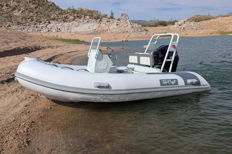 Slide: The Image of 2027 Tide Craft San Juan 11 inflatable boat on a rocky shoreline. - 17