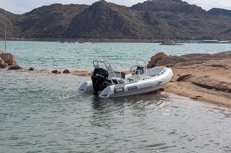 Slide: The Image of Tide Craft San Juan 11 boat docked on a rocky lakeshore, 2027 model. - 19
