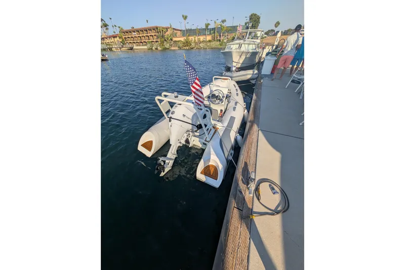 Slide: The Image of 2027 Tide Craft San Juan 11 boat docked, featuring an American flag and calm waters. - 22