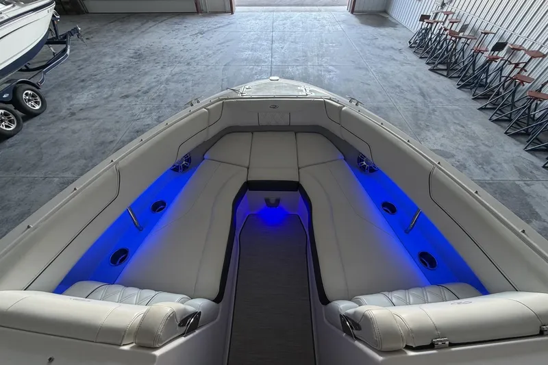 Slide: The Image of 2019 Regal LS6 boat interior with blue LED lighting and plush seating in a garage. - 16