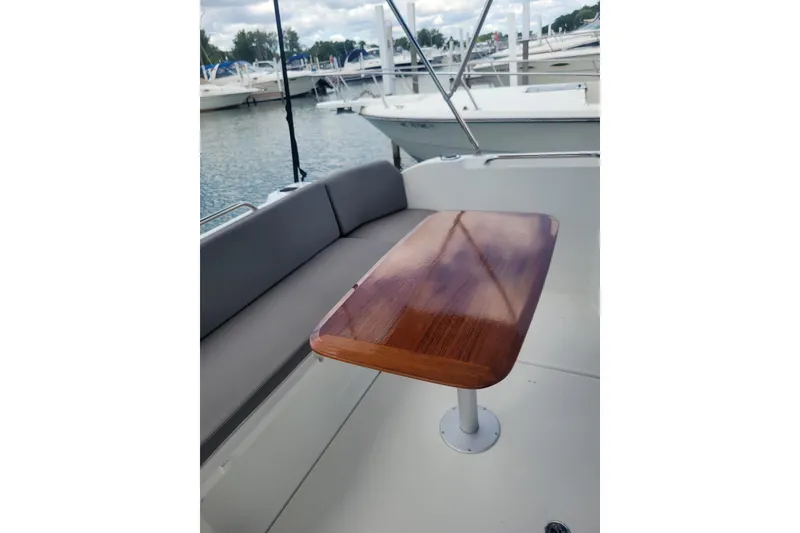 Slide: The Image of 2019 Beneteau Antares 23 boat interior with wooden table and cushioned seating. - 4