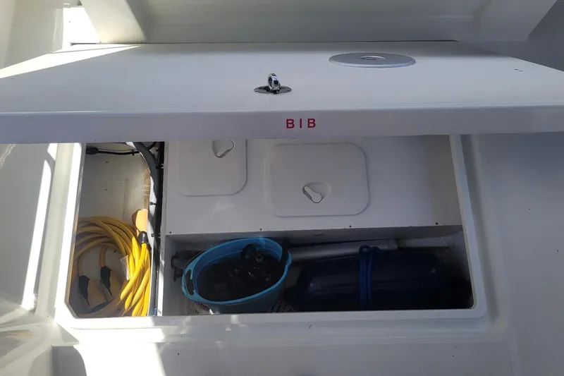 Slide: The Image of Storage compartment on a 2019 Beneteau Antares 23 boat, containing a hose and bucket. - 5
