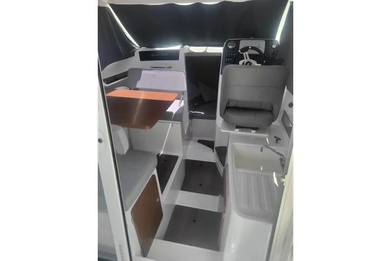 Slide: The Image of Interior of 2019 Beneteau Antares 23 boat, featuring helm, seating, and compact kitchenette. - 8