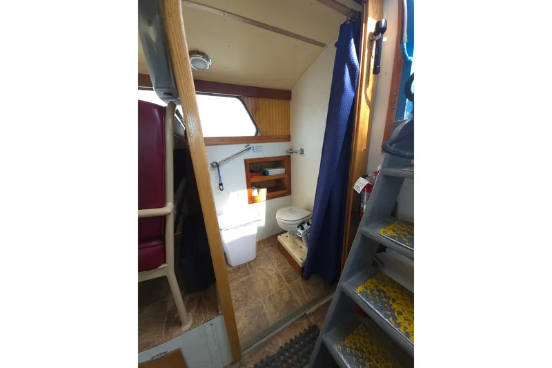 Slide: The Image of Interior of 1974 Breaux's Bay Craft boat, featuring a compact bathroom with toilet and curtain. - 21