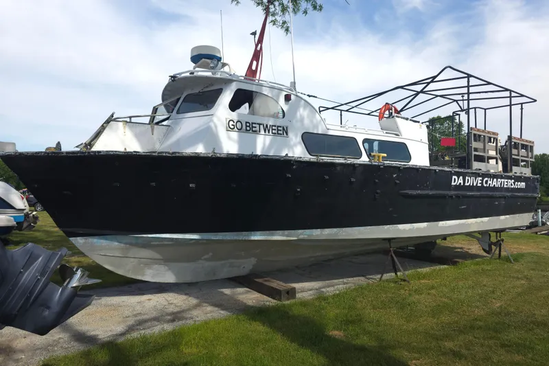 Slide: The Image of 1974 Breaux's Bay Craft passenger boat on land, labeled "GO BETWEEN" and "DA DIVE CHARTERS.com". - 3
