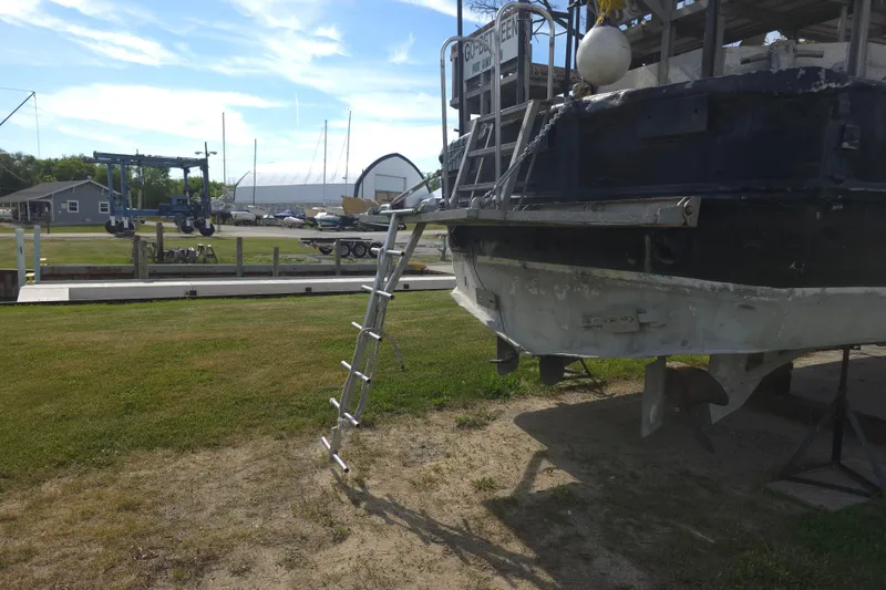 Slide: The Image of 1974 Breaux's Bay Craft passenger boat on land with ladder and marina background. - 6