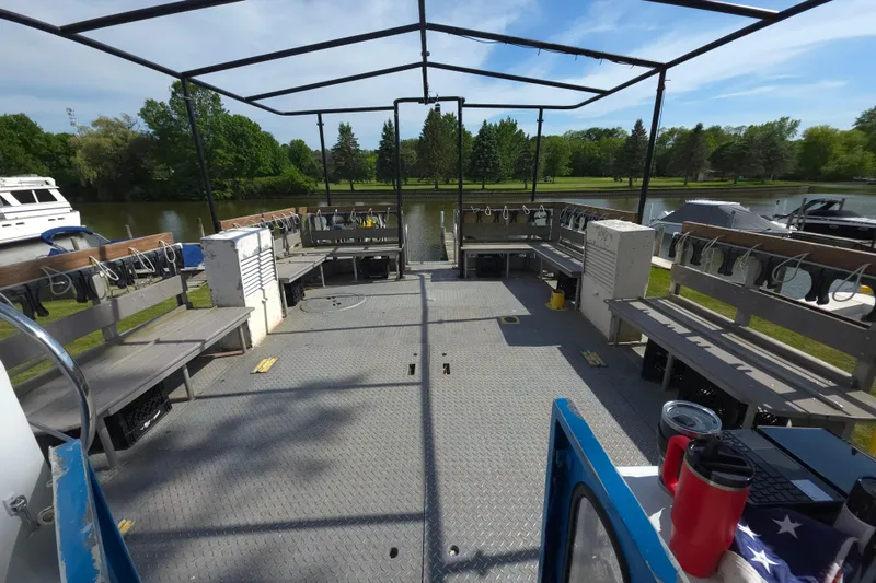 Slide: The Image of 1974 Breaux's Bay Craft passenger boat interior with benches, docked by a scenic river. - 9