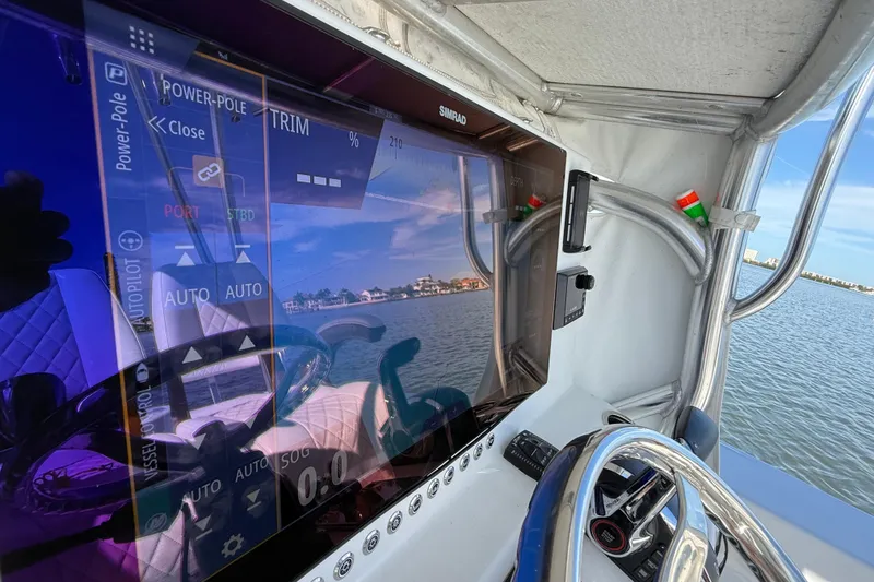 Slide: The Image of 2024 East Cape 25 Hybrid boat dashboard with Simrad display and steering wheel. - 23