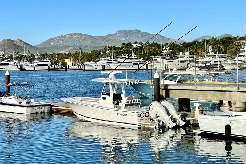 Slide: The Image of 2022 Regulator 28 boat docked in a marina with scenic mountain backdrop. - 15