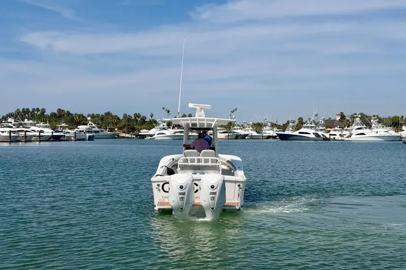 Slide: The Image of 2022 Regulator 28 boat cruising in a marina with yachts and palm trees. - 3